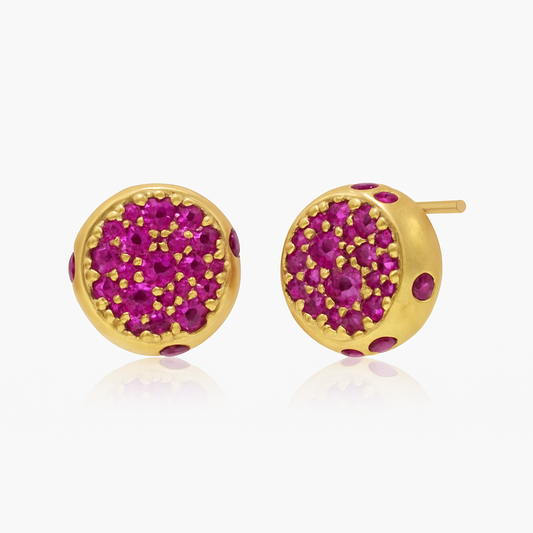 Round dome stud earrings crafted in solid gold and encrusted with natural ruby gemstones in a pavé setting. Modern minimalist design, ideal for gifting.