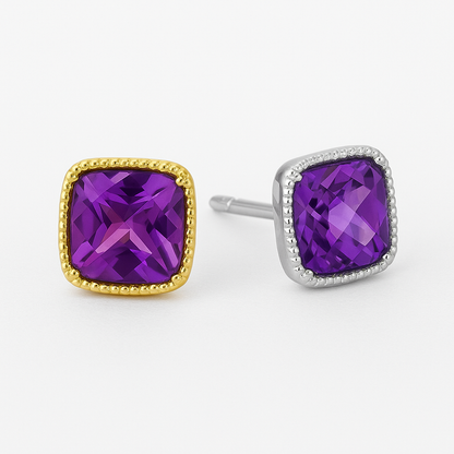 Cushion-cut amethyst stud earrings set in a square gold bezel with delicate beaded detailing along the border, displayed on a soft cream background with a gentle reflection.